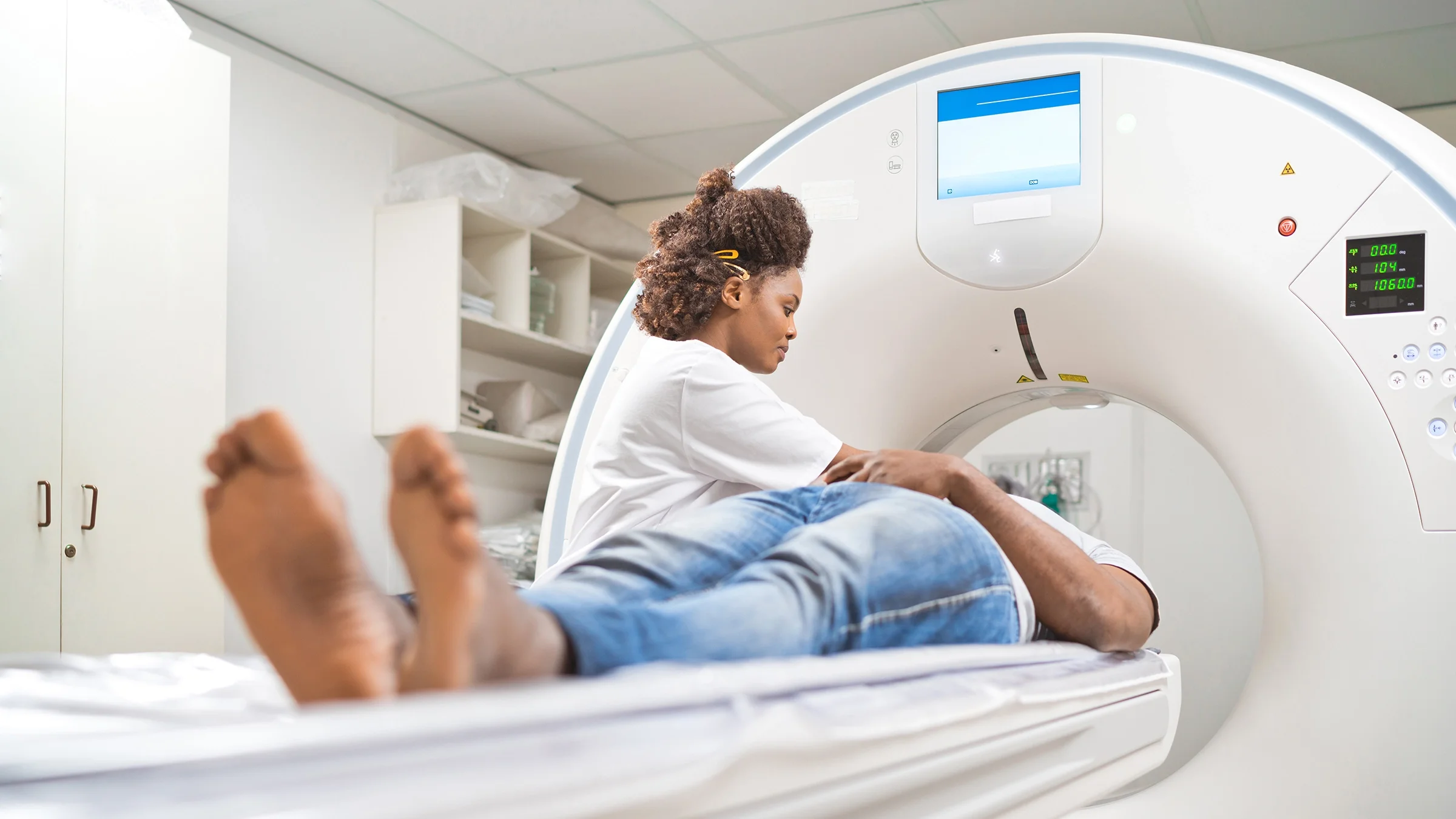 A healthcare professional tends to a man lying down on a scanner bed. 