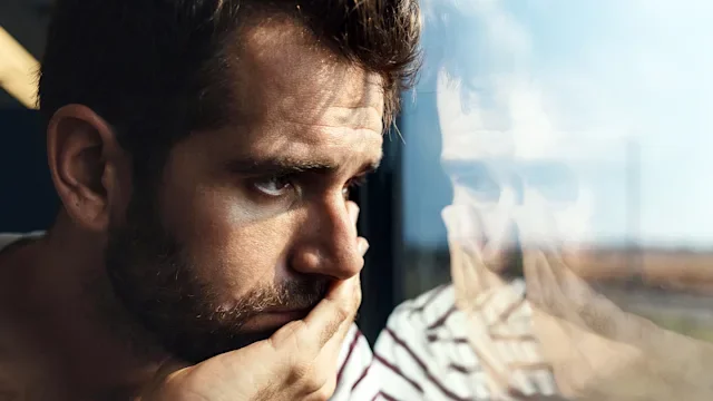 Mental-health: sad man looking through window 606671220