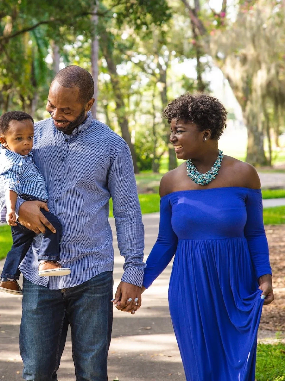 Gabrielle Davis is pictured with her husband and toddler son walking in a park.