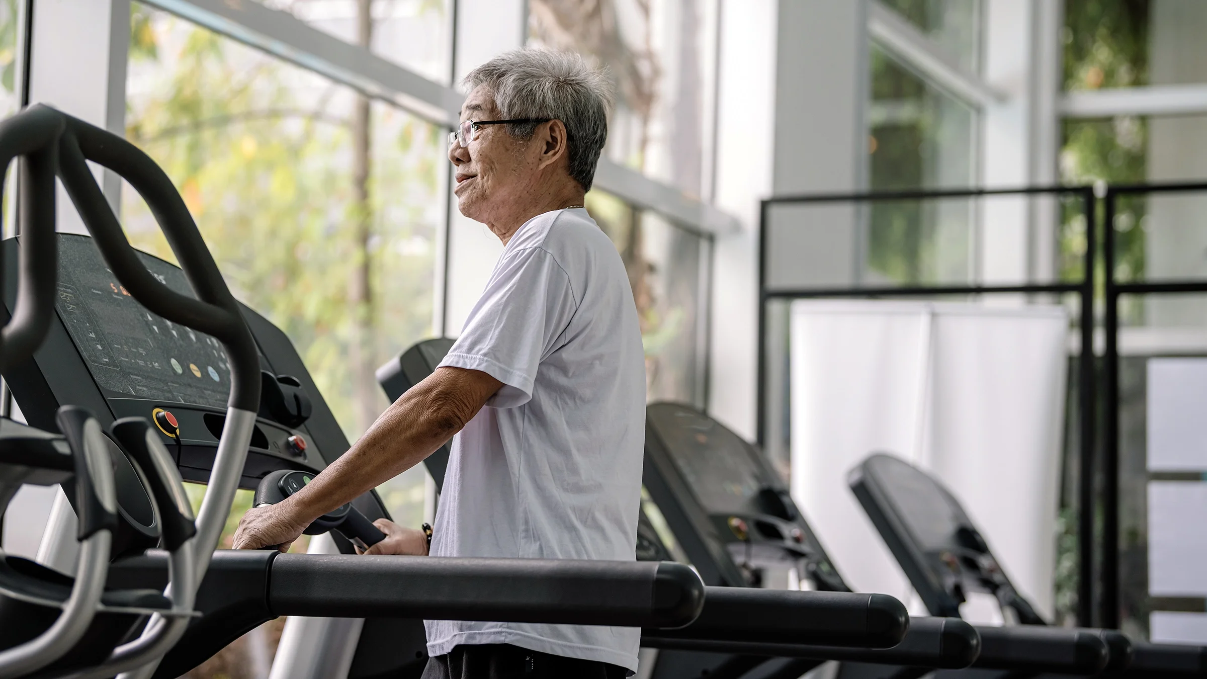 Active senior working out on a treadmill in a gym.