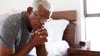 Mental health: Prolonged grief: sad senior man sitting on bed-1132798012