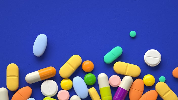 Various colorful pills on a deep-blue background. The pills are filling the bottom of the frame, up to the middle.