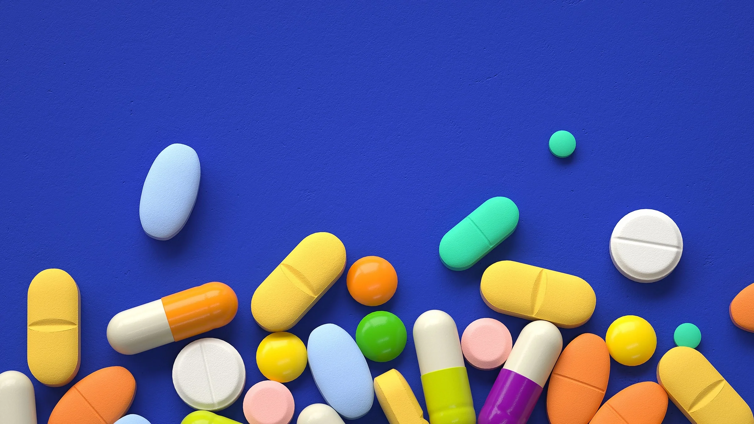 Various colorful pills on a deep-blue background. The pills are filling the bottom of the frame, up to the middle.