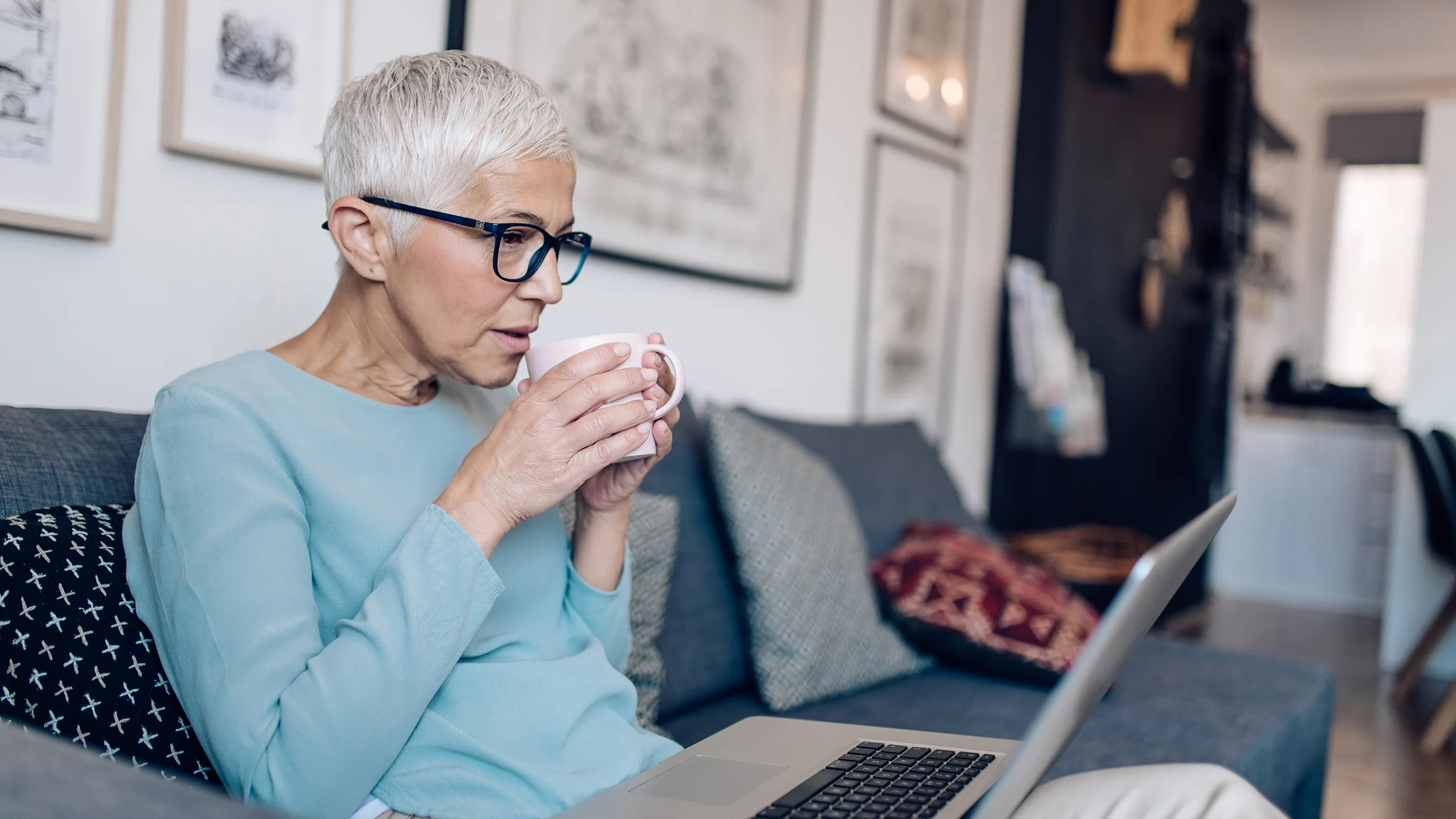 A senior woman uses her laptop in her living room.