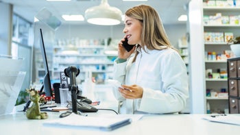 Pharmacists: Insurance: pharmacist on phone holding medicine 1482189403