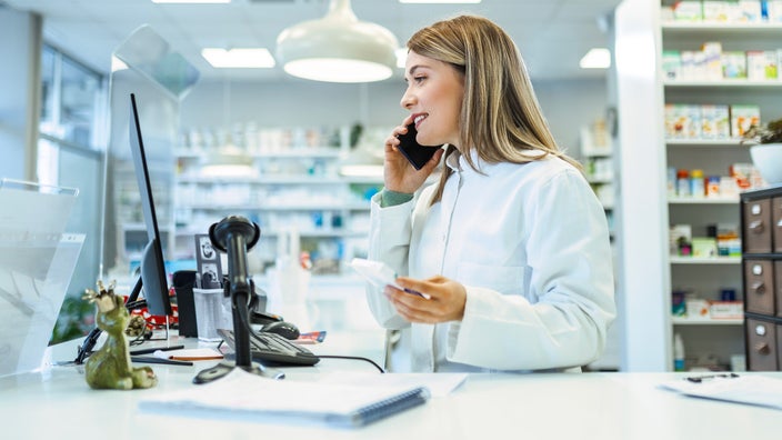 A pharmacist on a phone call, holding a medication.
