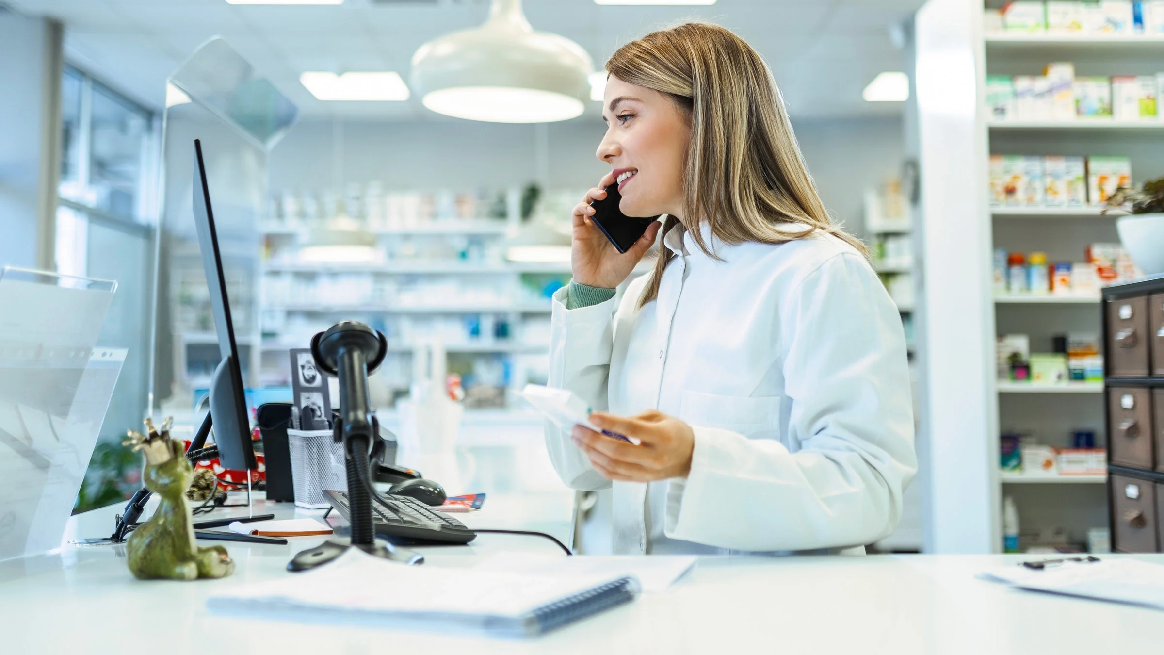 A pharmacist on a phone call, holding a medication.