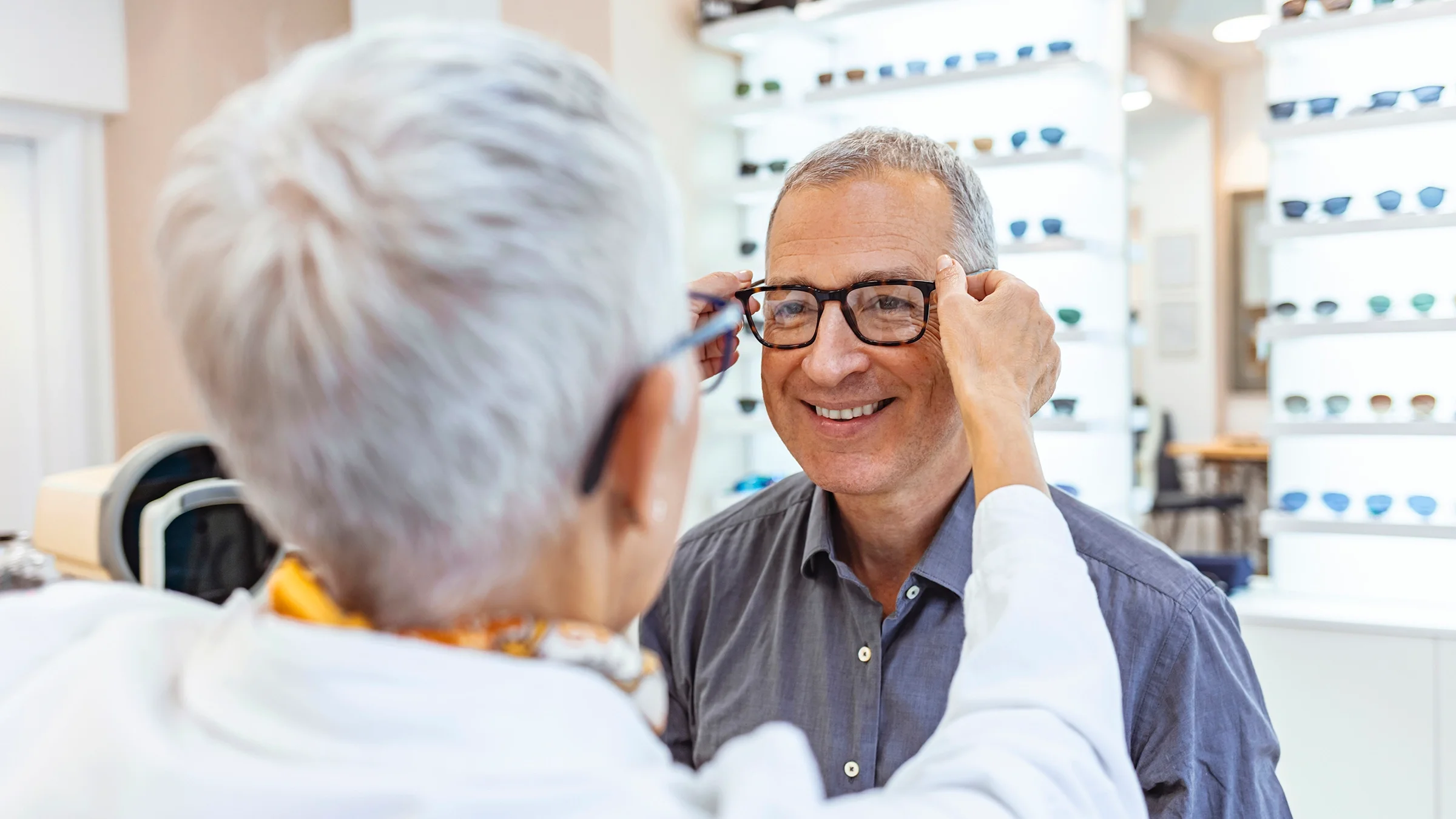 Older man trying on glasses at the eye doctor.
