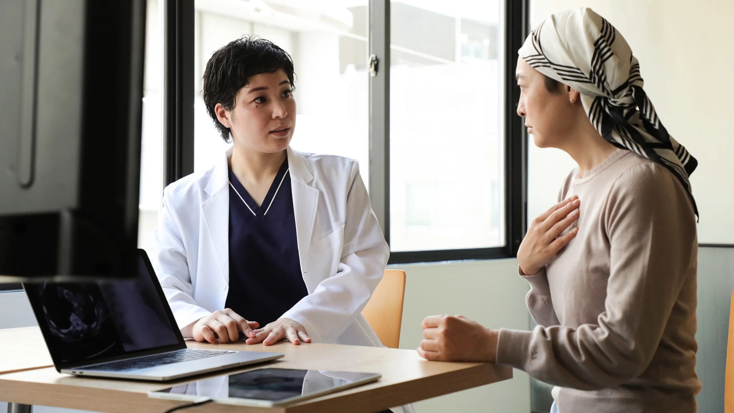 A cancer patient and doctor talking at a desk.