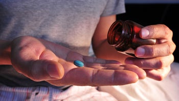 Viagra: taking blue pill close-up 1133787163