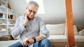 Heart health: senior man taking pulse at home-1310179091