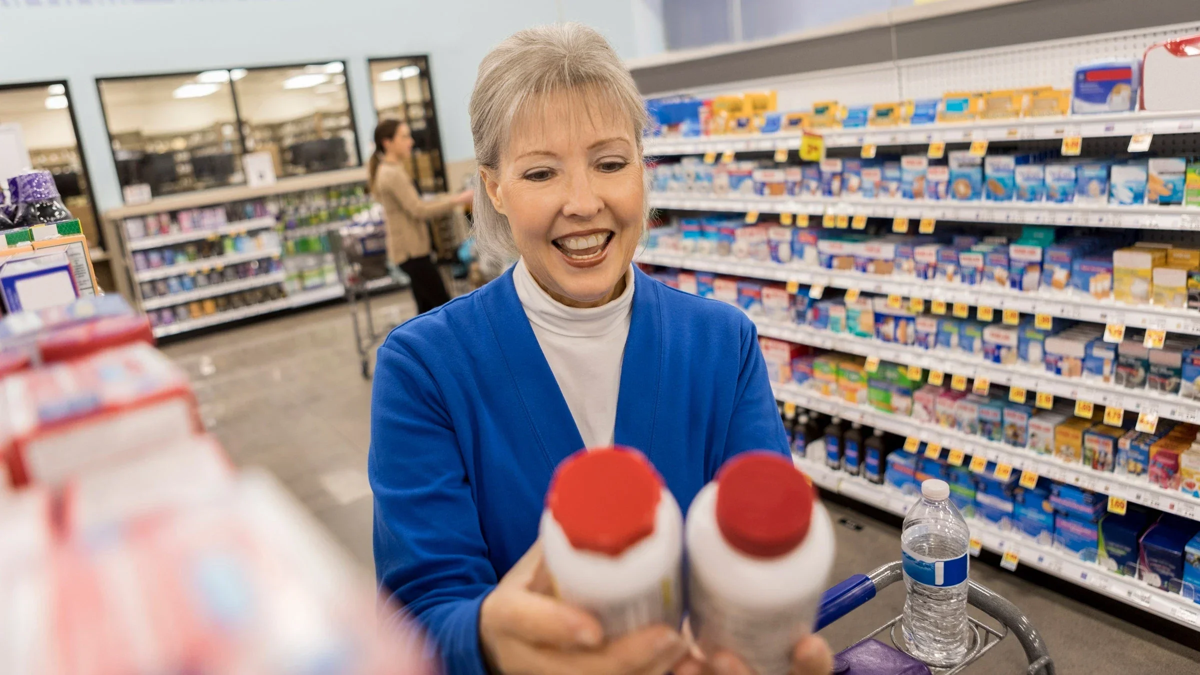 A customer holding two pill bottles in a pharmacy aisle.
SDI Productions/E+ via Getty Images