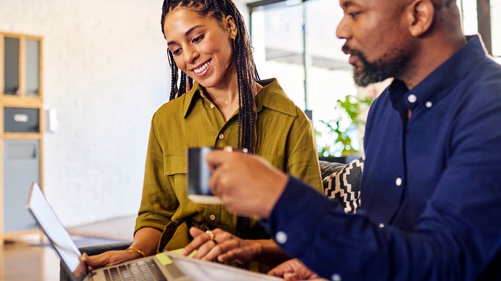 A couple is looking at a laptop and paperwork.