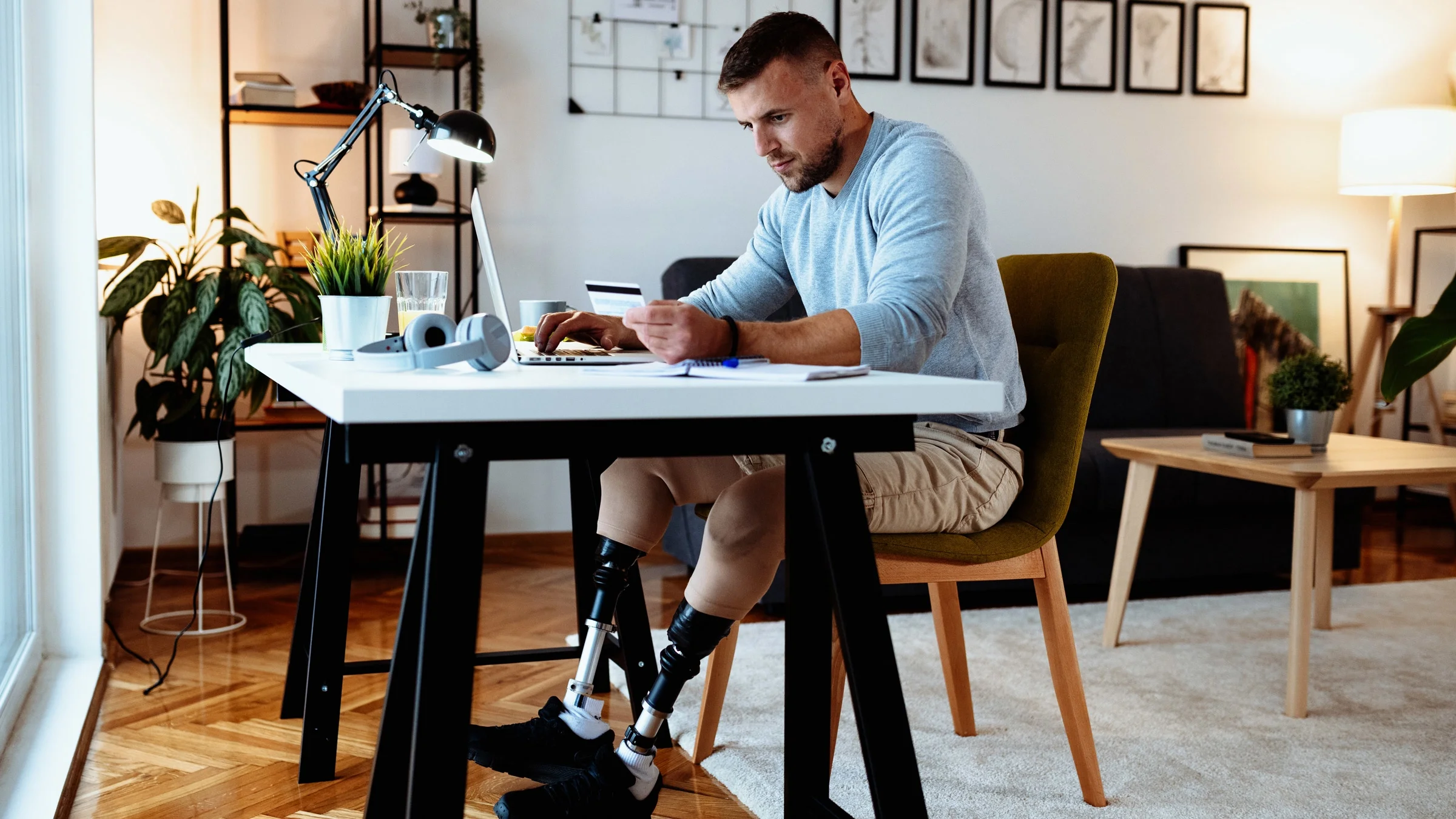 A disabled man making a card purchase at his desk. 