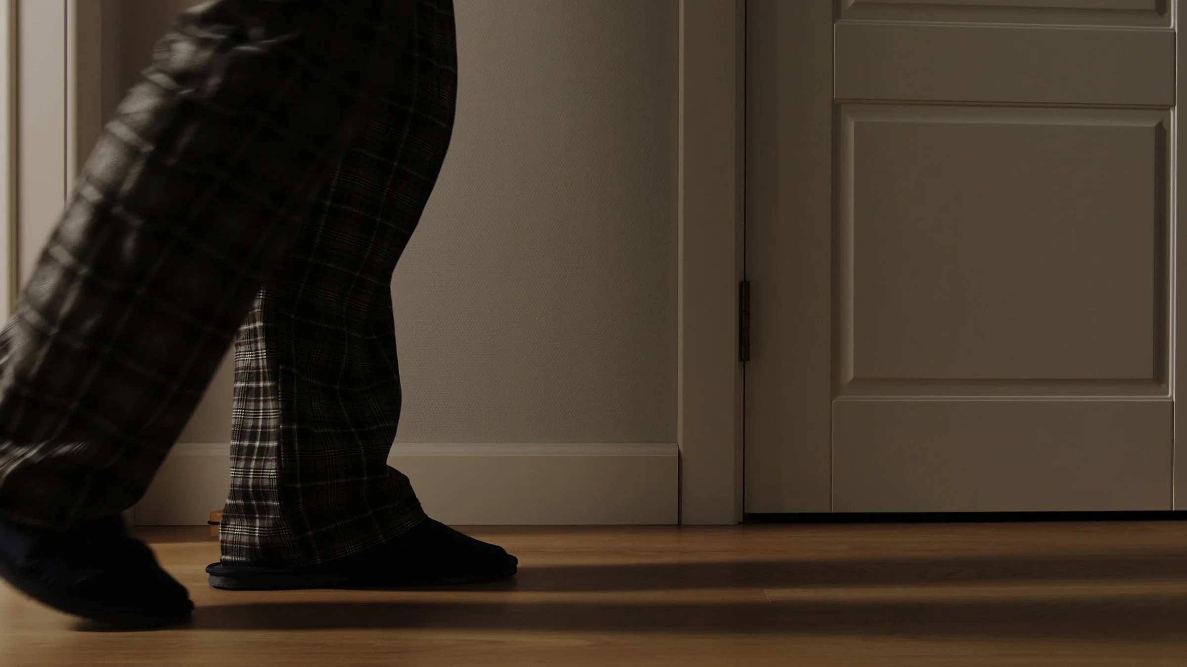 Cropped image of someone's feet walking indoors at night.
