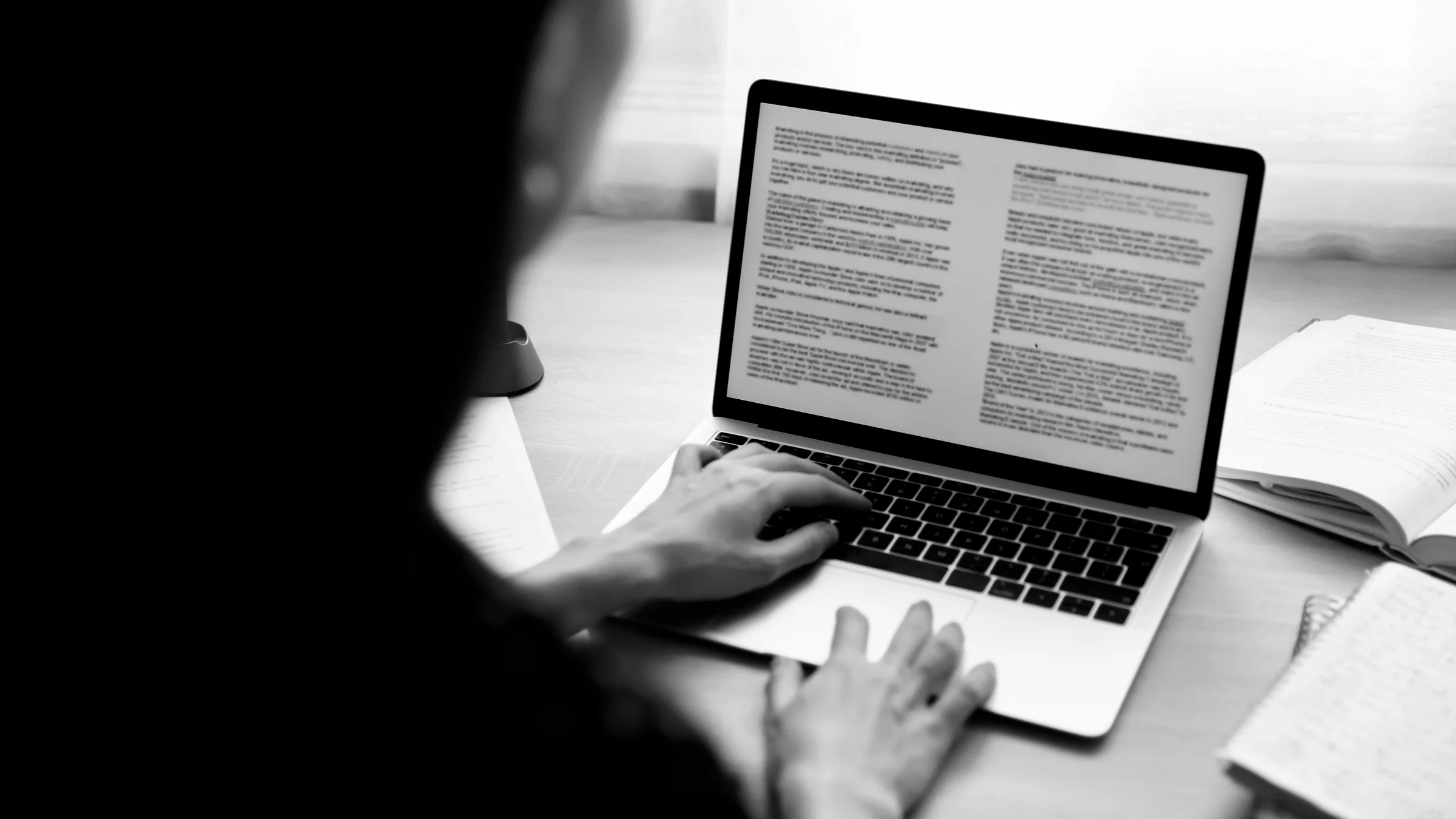 Person using a laptop to review legal paperwork. You can only see their back and they are out of focus.