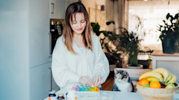 A young adult organizing their pill container at their kitchen counter, next to their cat.
OKrasyuk/iStock via Getty Images Plus 