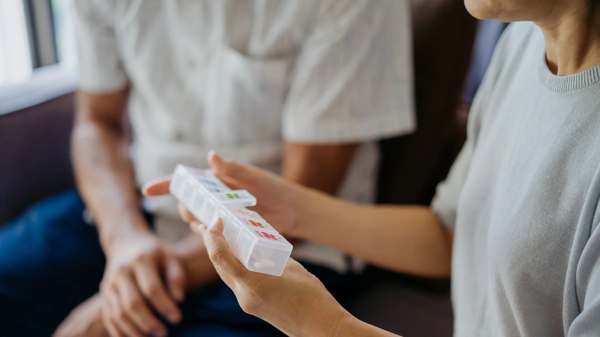 A woman takes medicine from a pill organizer.