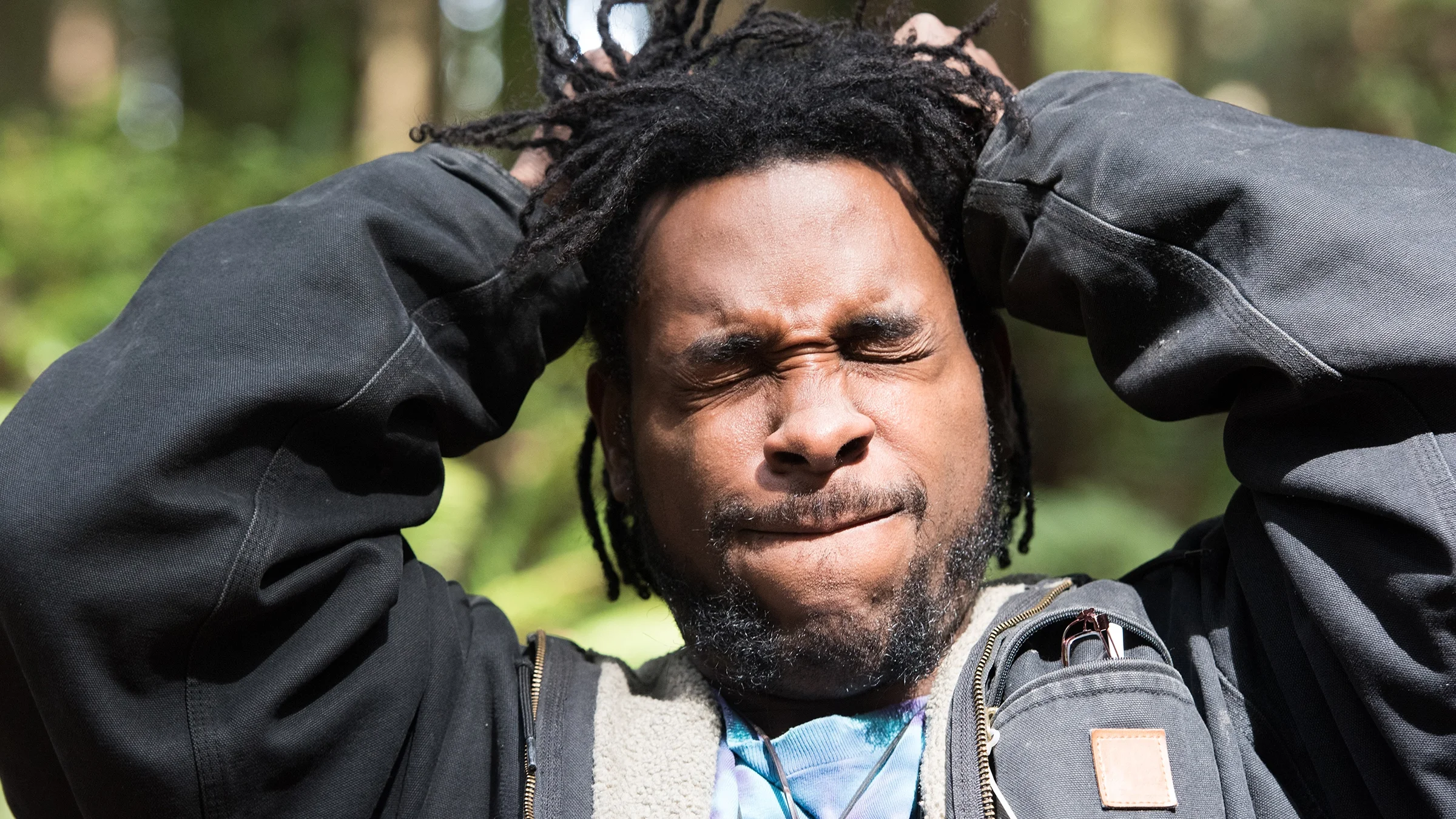 Man suffering from ringing in his ears. He is squinting and pulling at his hair.