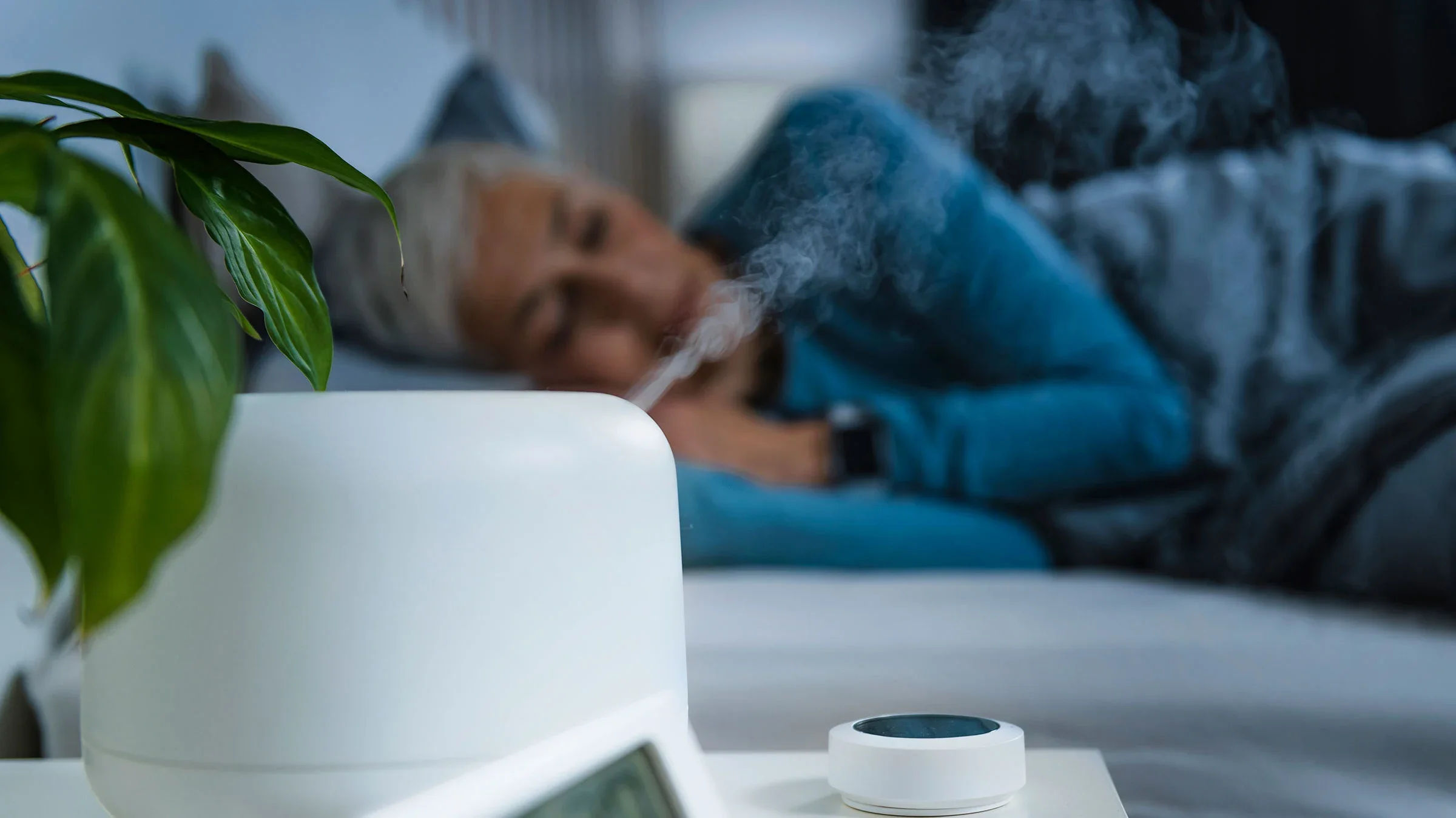 A woman is asleep in bed while using a humidifier.
microgen/iStock via Getty Images Plus