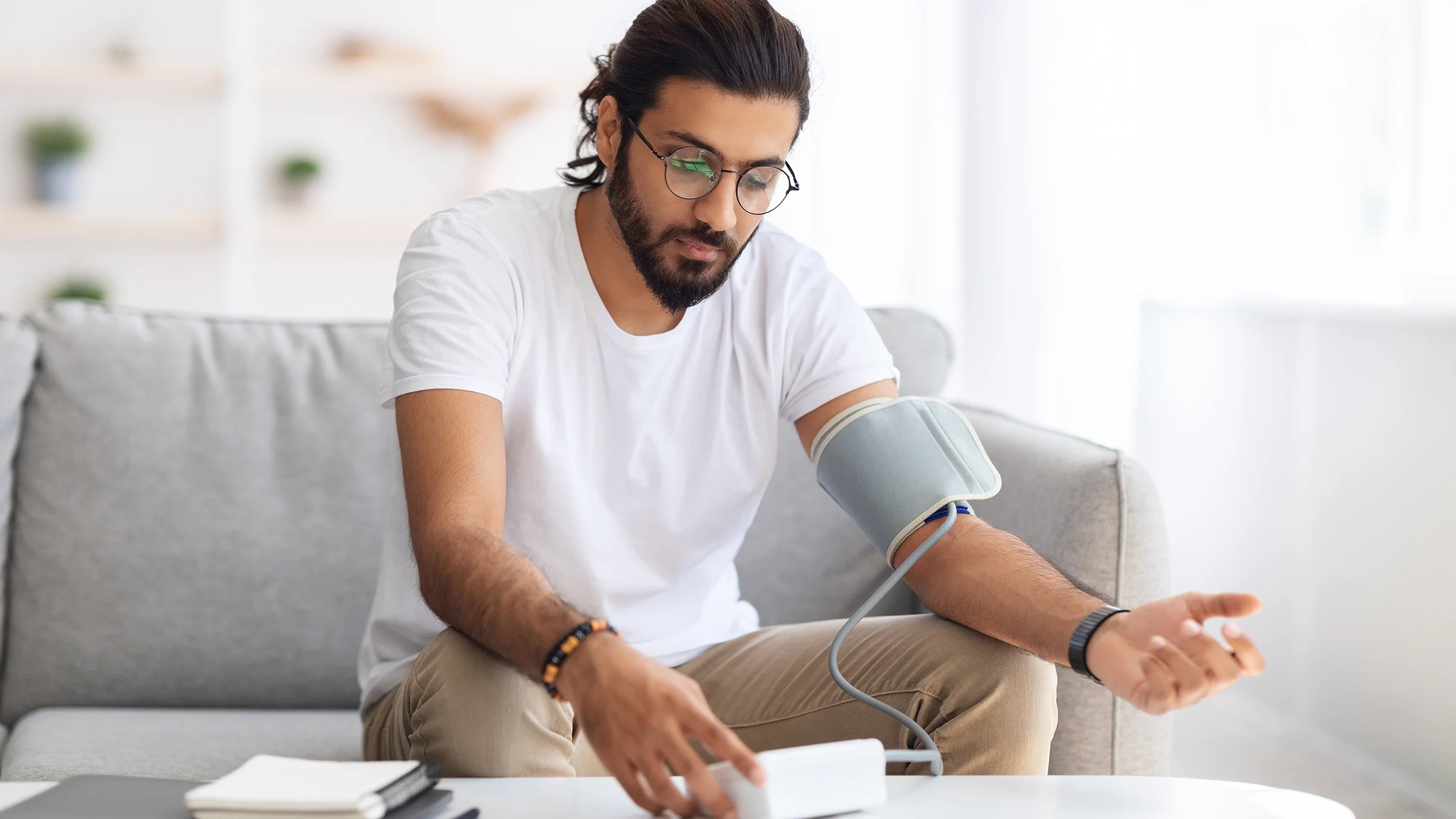 A man sits and checks his blood pressure at home.