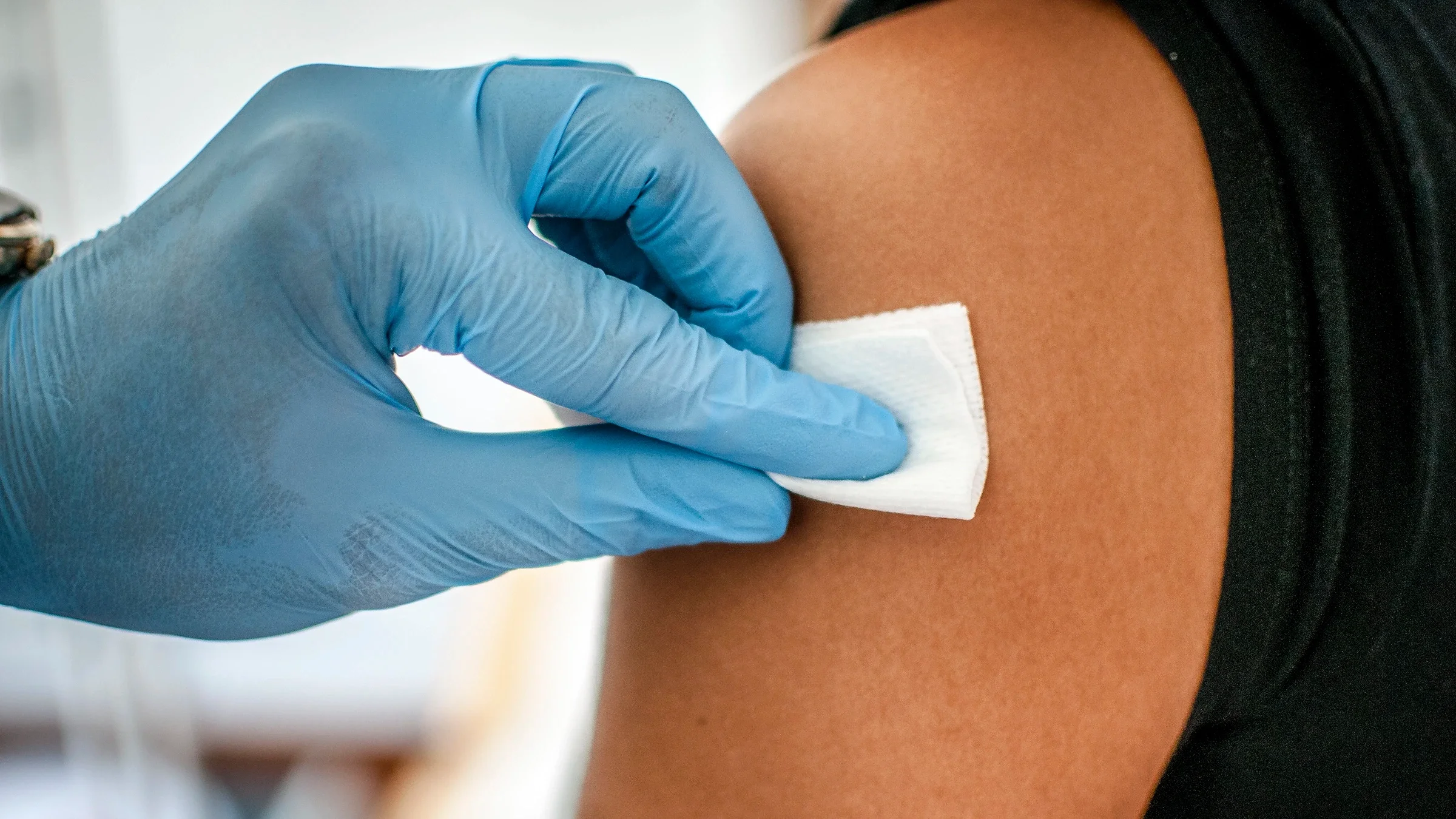 A healthcare worker is disinfecting an arm for an injection.