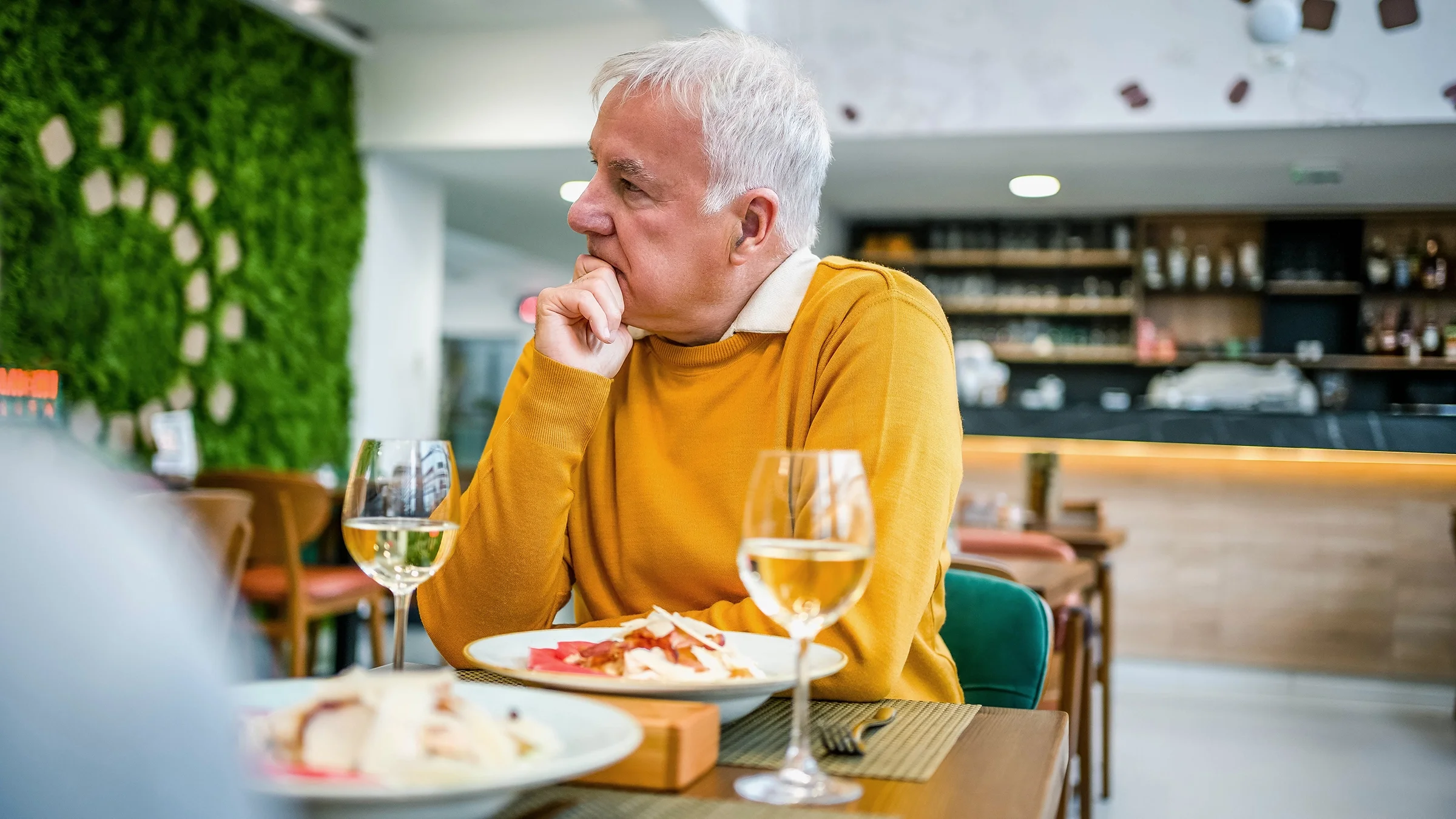 A man eats a meal with wine in a restaurant.