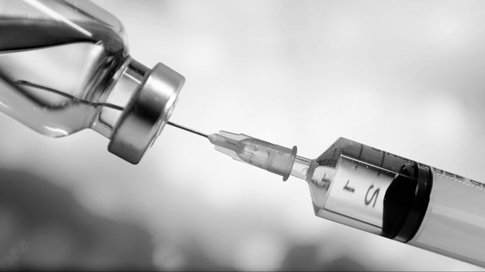 Black and white image of a syringe drawing liquid from a vial.