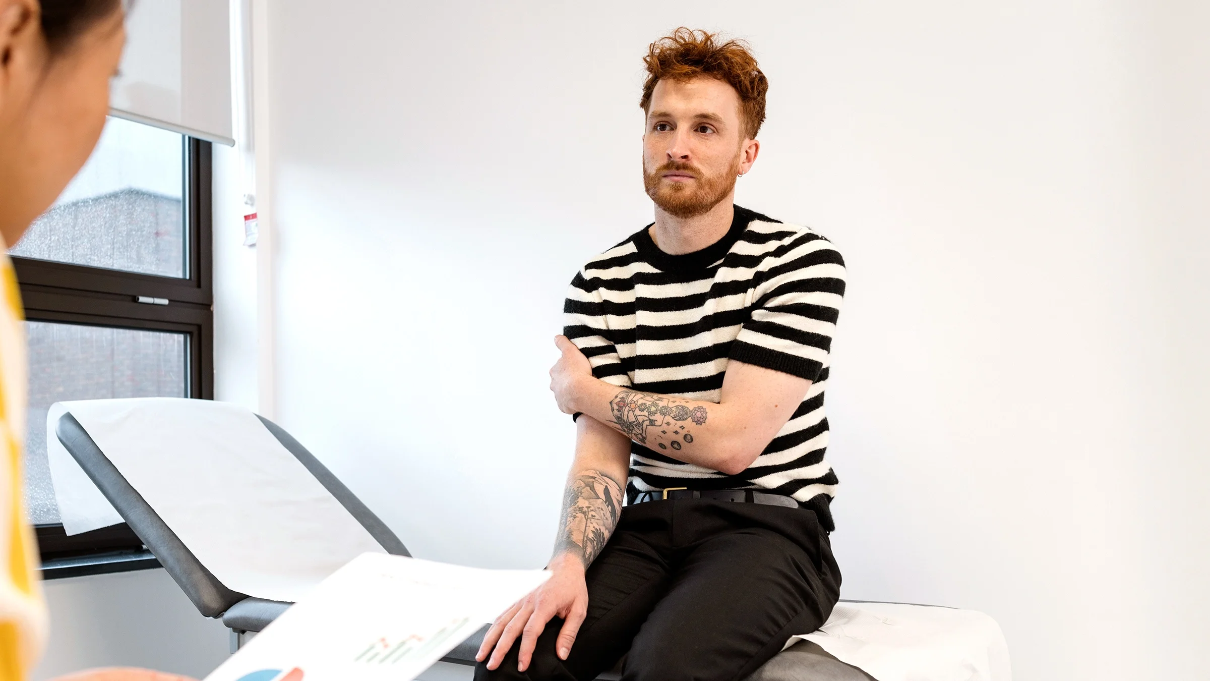 A man speaks to a nurse during a medical checkup.