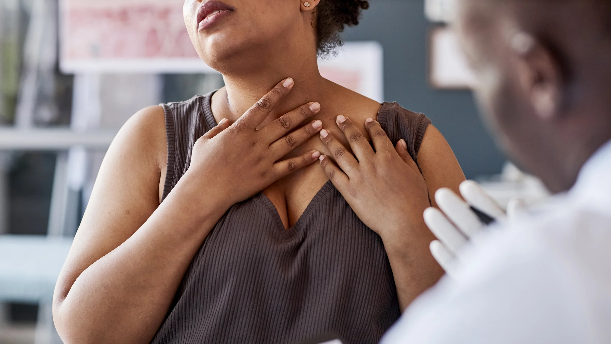 A woman touches her neck during a consultation with a healthcare professional.