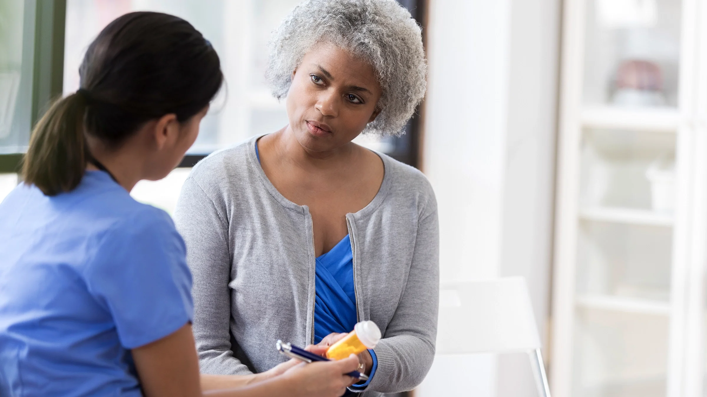 A woman receives prescription medication from a healthcare professional.