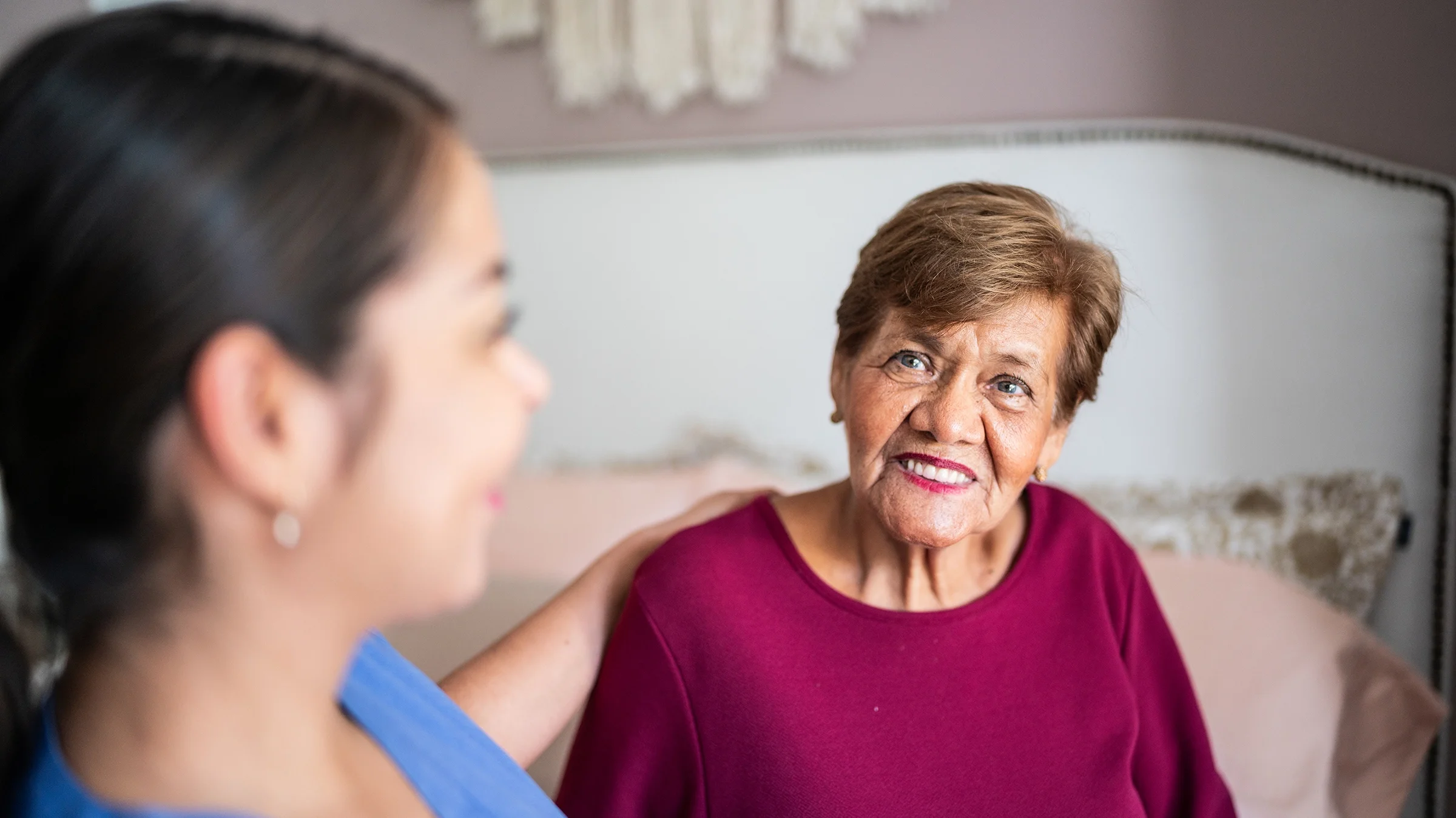 A home caregiver talks with an older woman under her care.