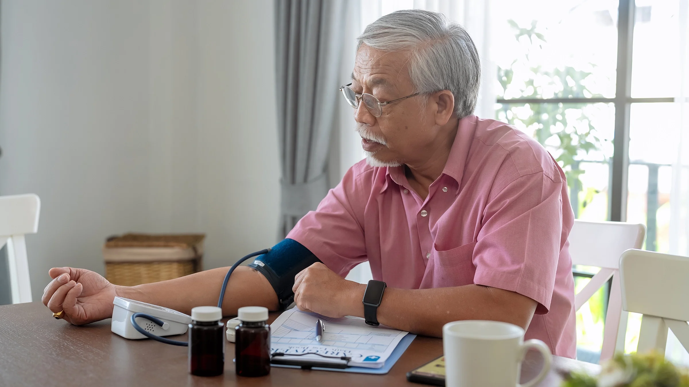 An older man is checking his blood pressure.