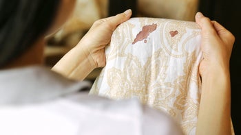 Health: Sexual health: blood on sheets woman looking at it-905386580