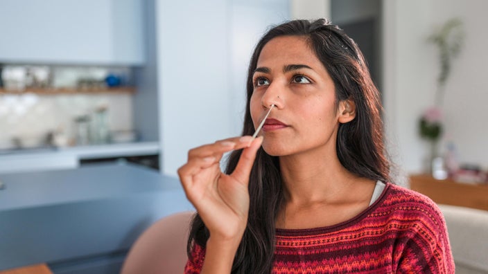 Woman swabbing nose for at-home Covid test.