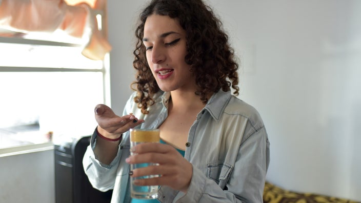 A transgender girl taking a pill.