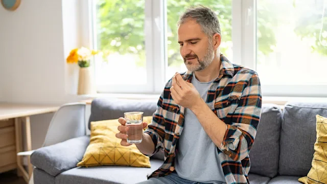ace-inhibitors: man taking medication at home 2150667196
