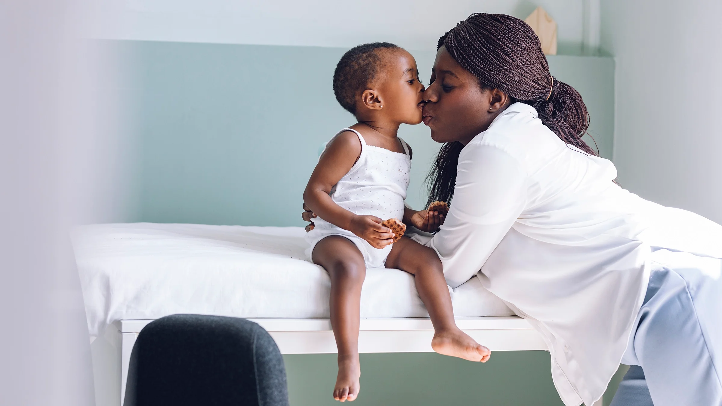 Mother and child kissing as they wait in the doctor’s exam room.