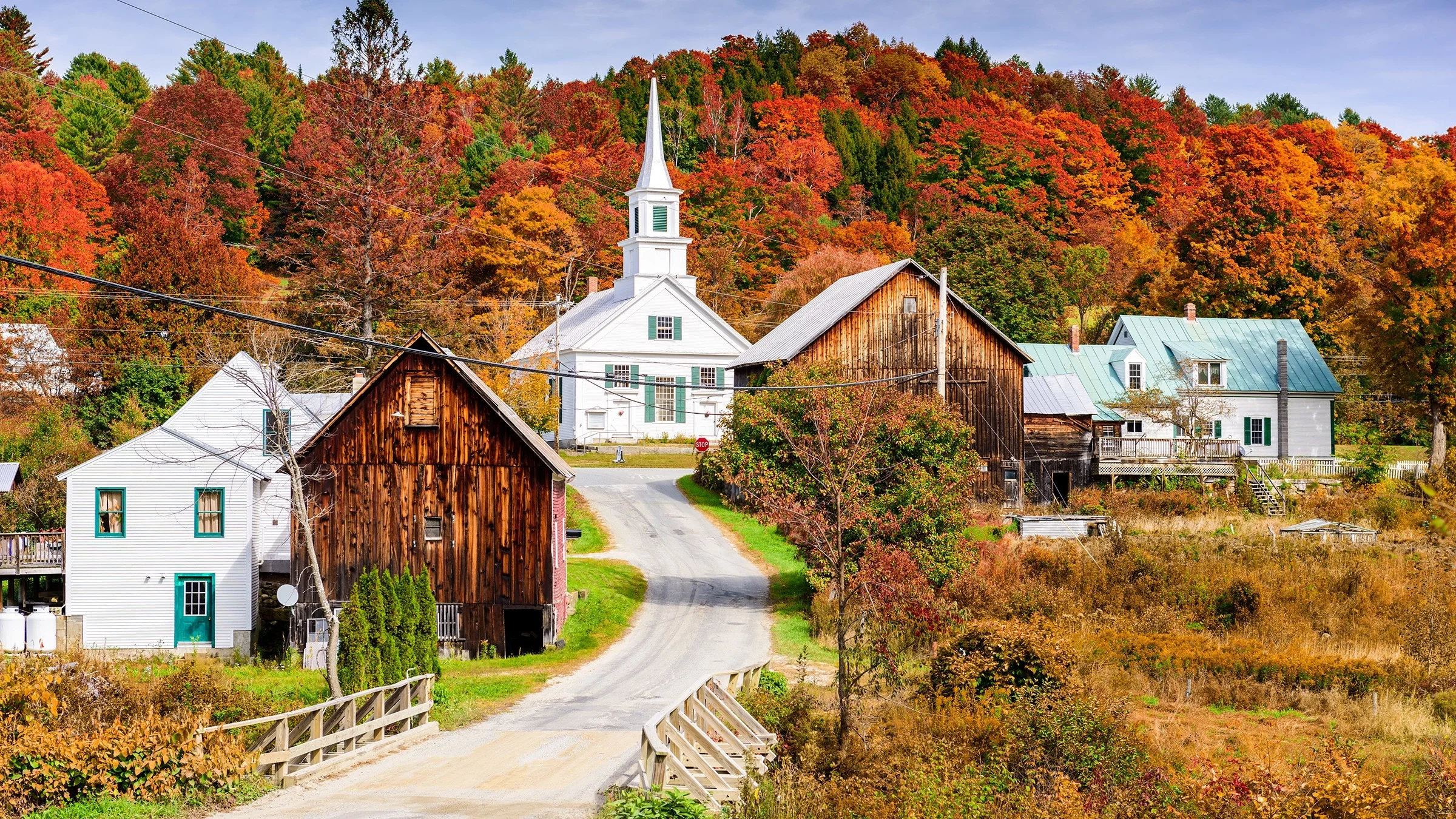 Landscape photo of a rural town. You can see barns and farmhouses as well as the local church.