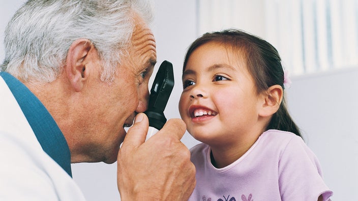 Doctor checking a young girl's vision. She is smiling cutely.