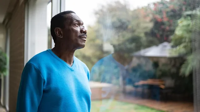 Senior health: man looking out window 1334849450