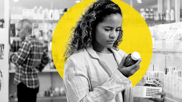 Black and white portrait of a woman reading a medication bottle label in the pharmacy. There is an added yellow graphic circle behind her.