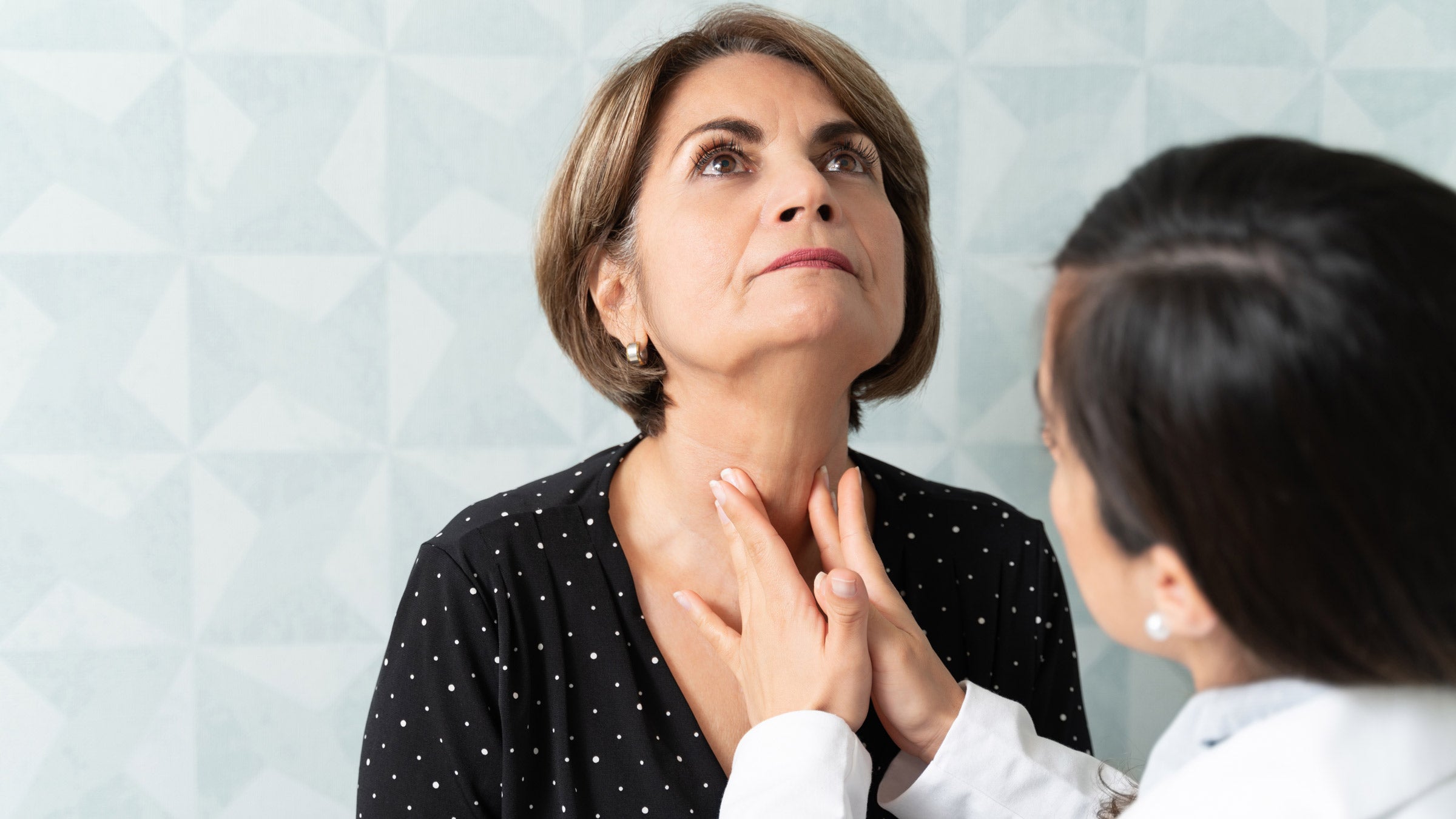 Thyroid: Hypothyrodism vs hyperthyroidism: doctor checking thyroid-1208841258