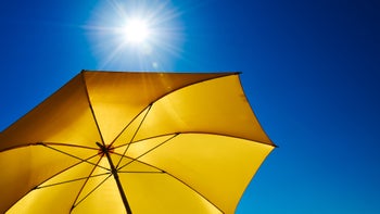 yellow sun umbrella with bright blue sky and sun-936342386