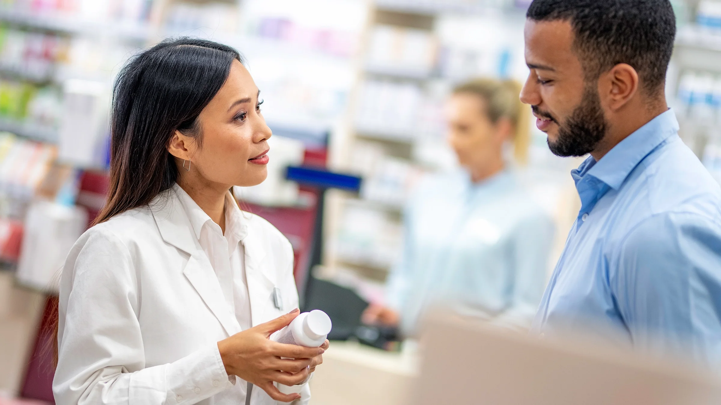 A pharmacist speaks with a customer about a medication.