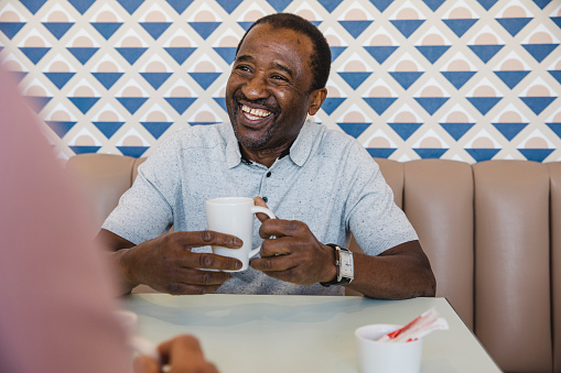 Older man enjoying his coffee and smiling in a diner booth.