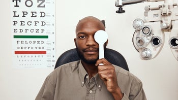 Eye: man covering eye in eye exam room-1305330199