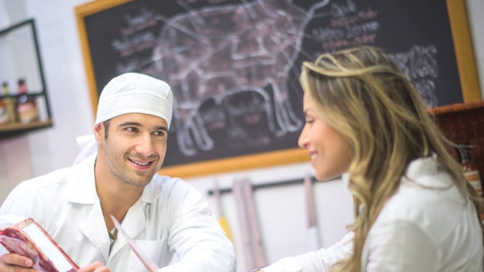 A butcher talking to a customer.