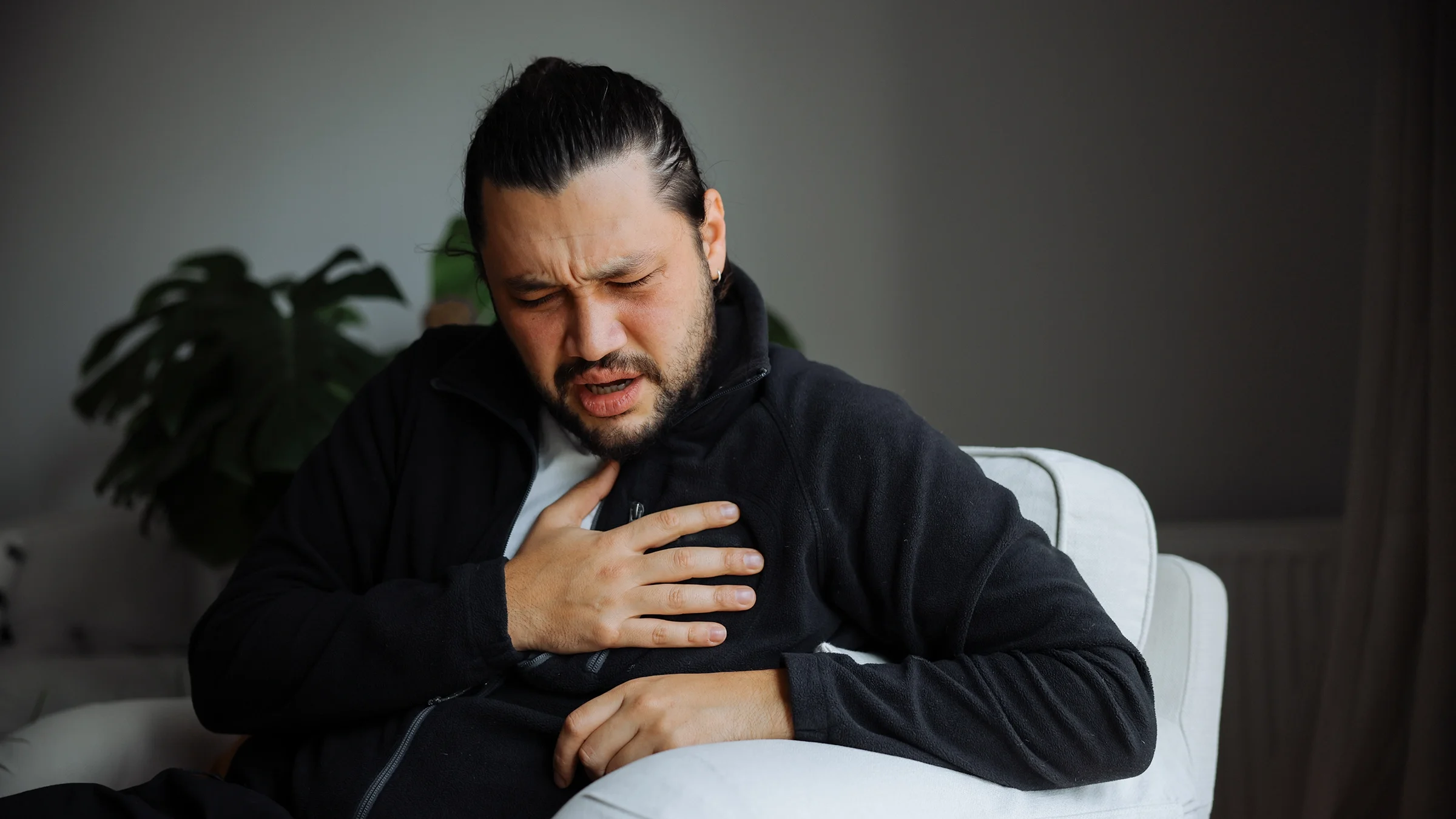 A man touches his chest as he experiences chest pain. 