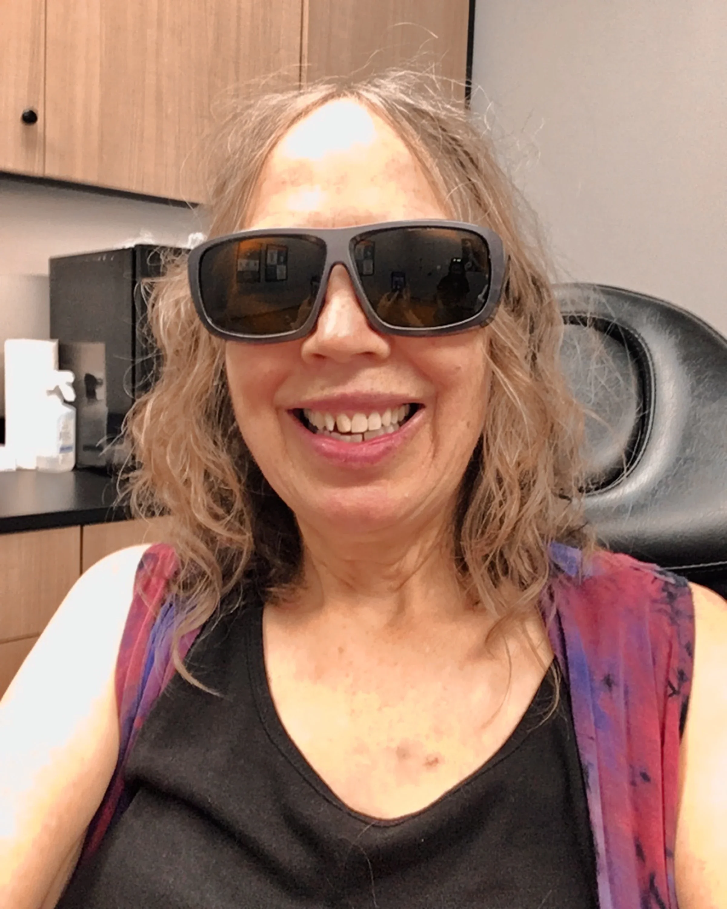 Maria Veres is pictured in a clinic, smiling and wearing protective glasses, ready to get her radiation tattoos removed.